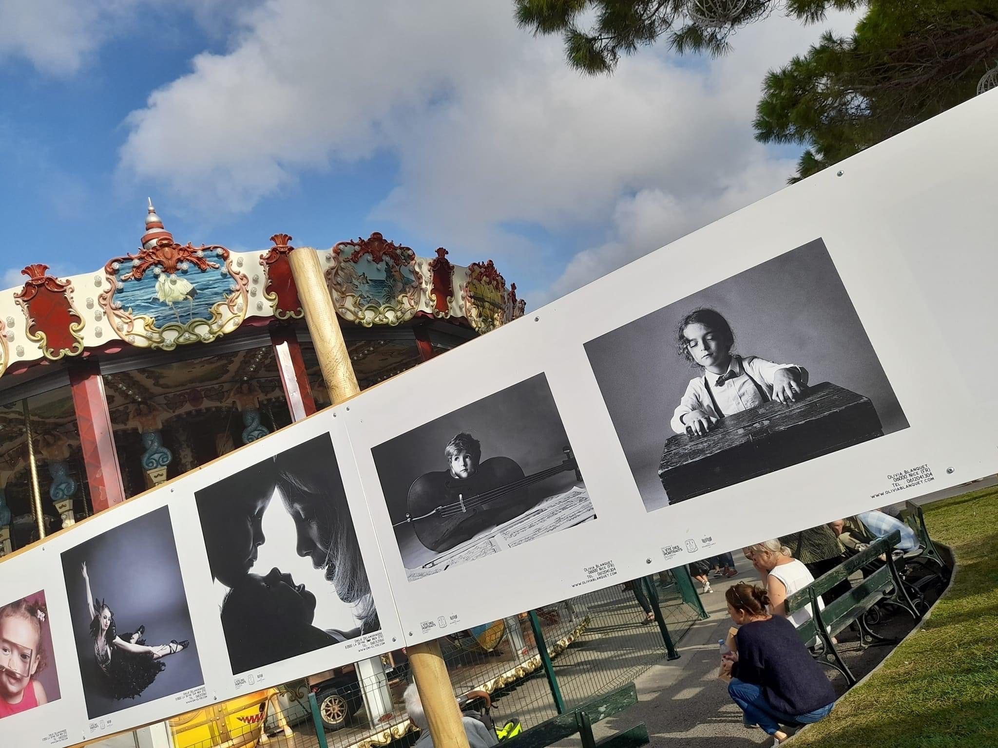 Exposition de portraits d'enfants en noir et blanc par Olivia Blanquet à L'été des Portraits, avec un manège en arrière-plan.