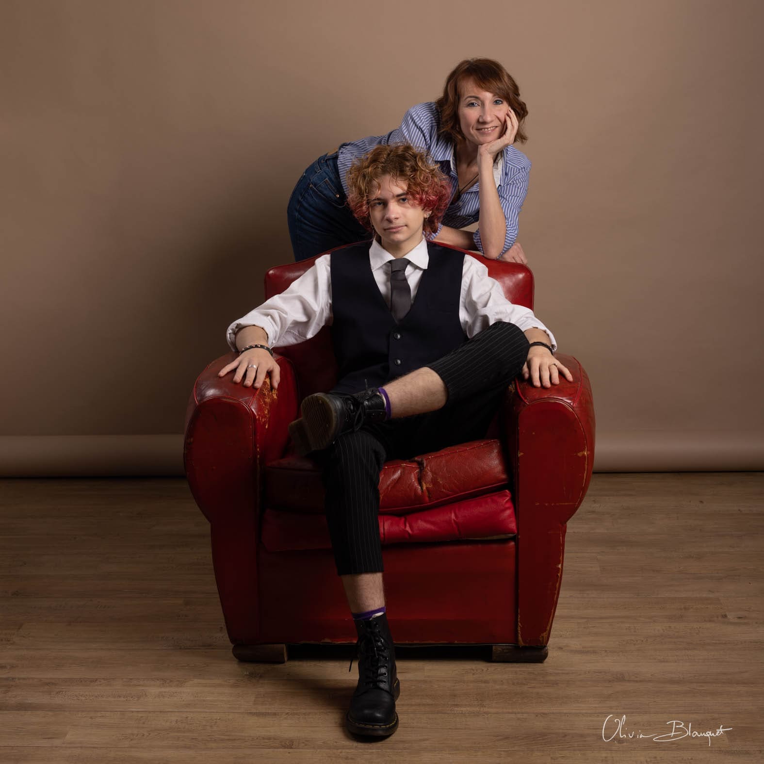 Photo de famille posée sur un fauteuil rouge en studio, Olivia Blanquet photographe professionnelle Nice.