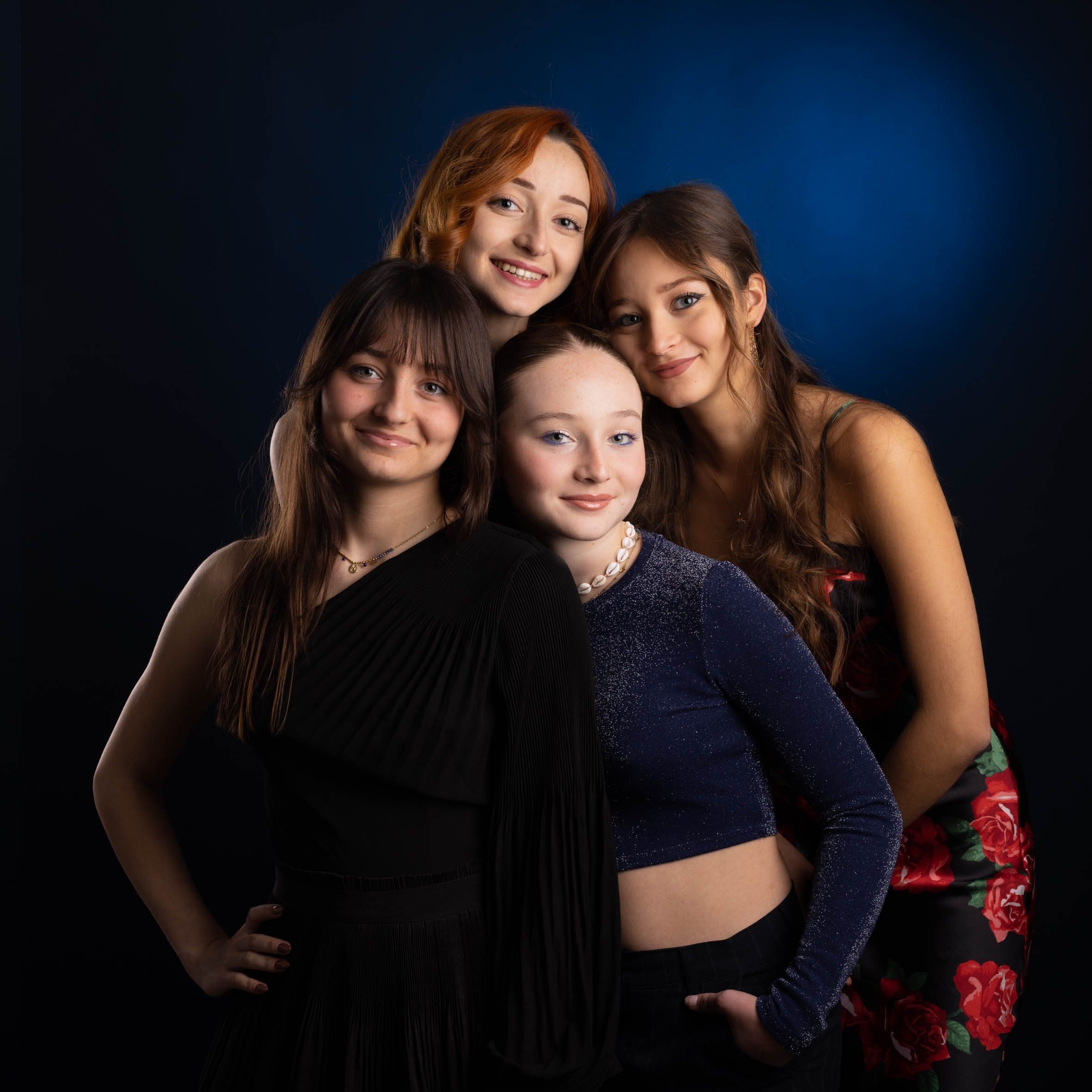 Portrait de groupe de quatre amies souriantes sur fond bleu, photographie de studio par Olivia Blanquet à Nice.